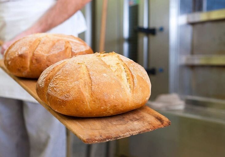 A person holding a wooden board with bread on it.