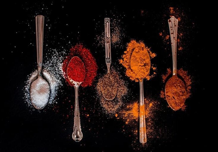 A group of spoons filled with different spices.