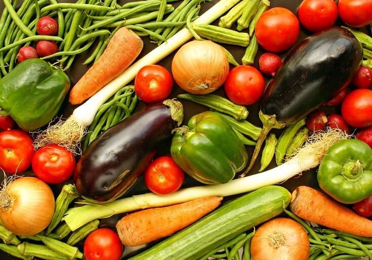 A pile of vegetables including tomatoes, carrots and eggplant.